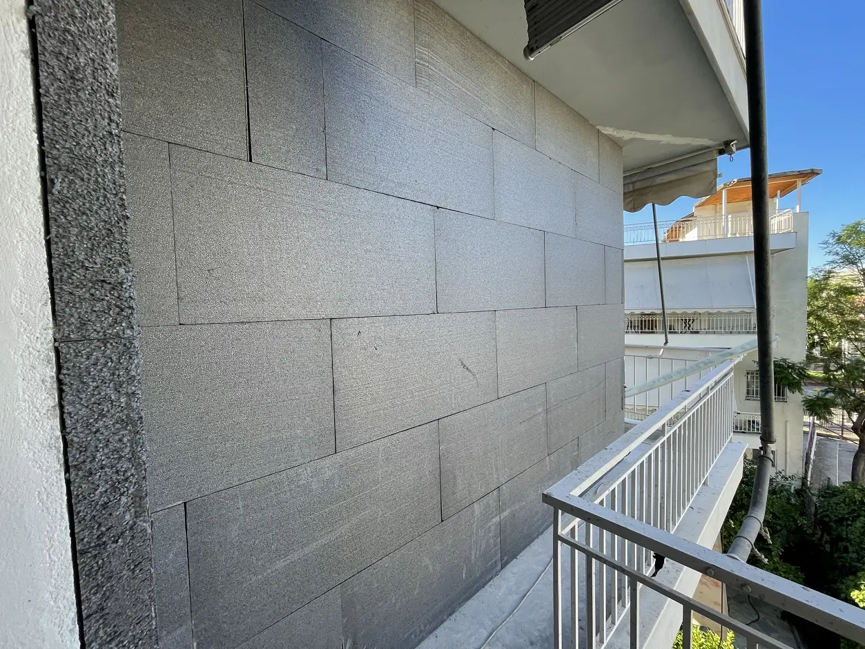 Εφαρμογή εξωτερικής θερμομόνωσης (θερμοπρόσοψη) με μονωτικές πλάκες γραφιτούχας πολυστερίνης σε τοίχο πολυκατοικίας.